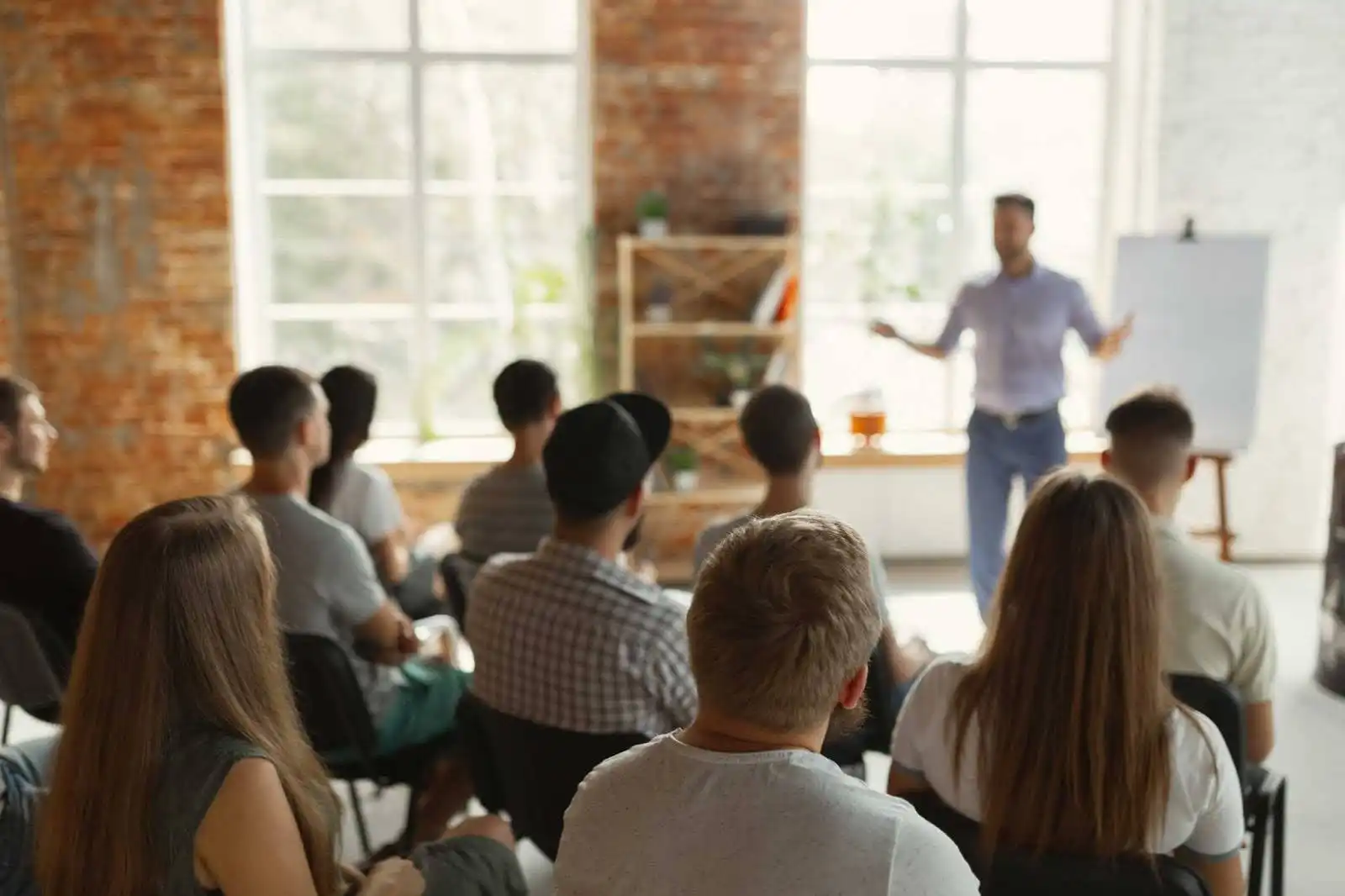 Palestra em ambiente de aprendizado com público atento, onde um orador apresenta conteúdo educativo em um espaço iluminado.