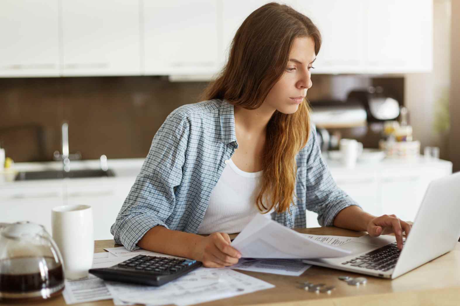 Estudante mulher com notebook e documentos, analisando propostas e renegociando dívidas do FIES pelo programa desenrola 2 em ambiente doméstico.