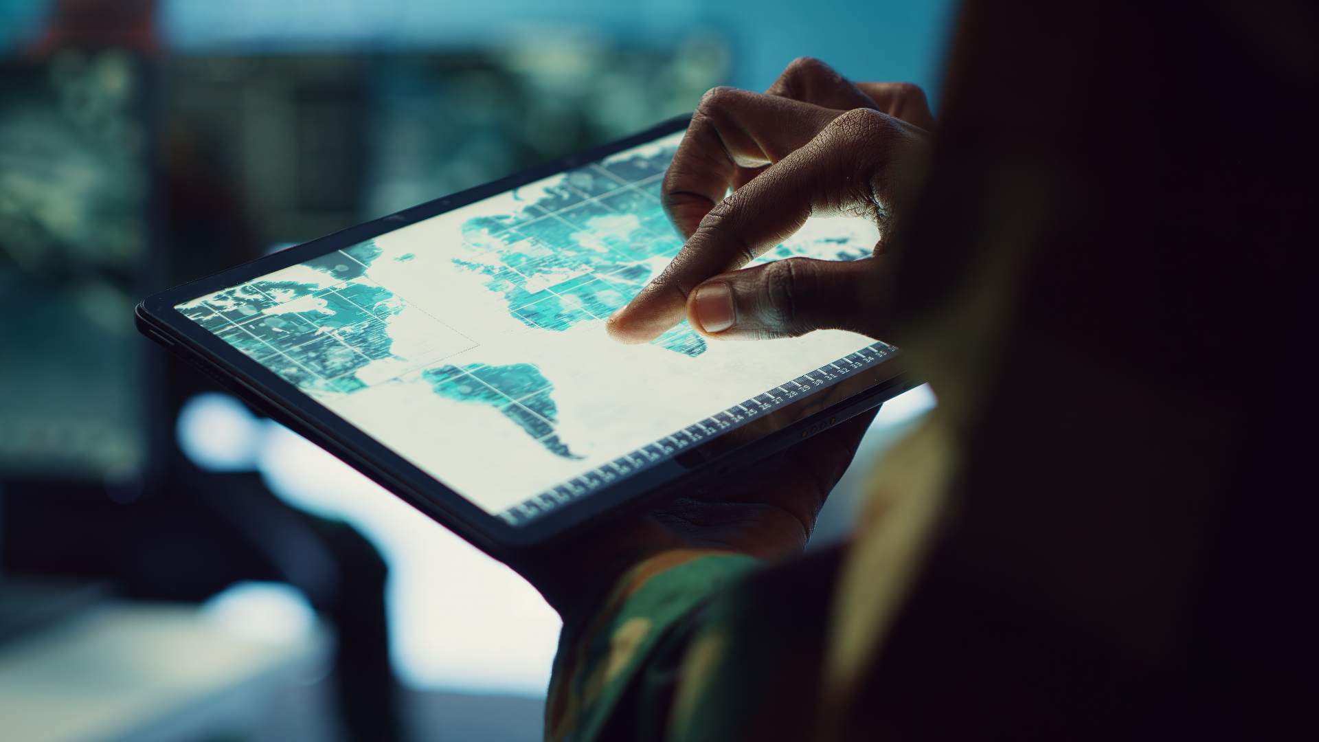 Pessoa usando um tablet com mapa digital e camadas espaciais, analisando territórios e dados geográficos com geotecnologias em Geografia.