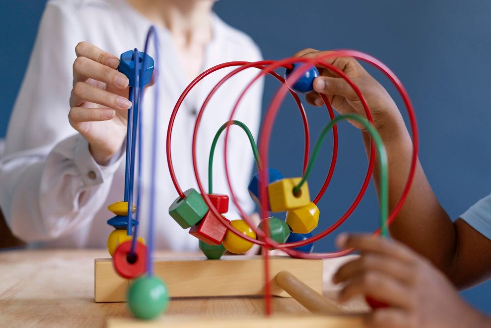 Criança brincando com um brinquedo educativo de encaixe e pinos coloridos, com fios coloridos e formas geométricas sobre uma base de madeira.