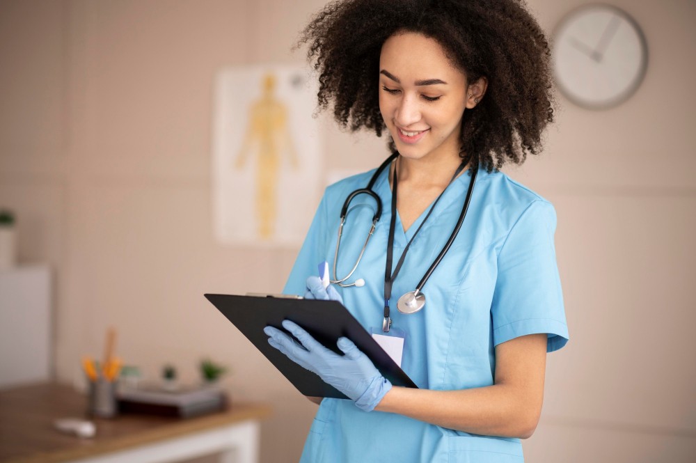 Médica sorridente com uniforme azul e estetoscópio, lendo anotações em prancheta digital em um ambiente clínico, pronta para atendimento