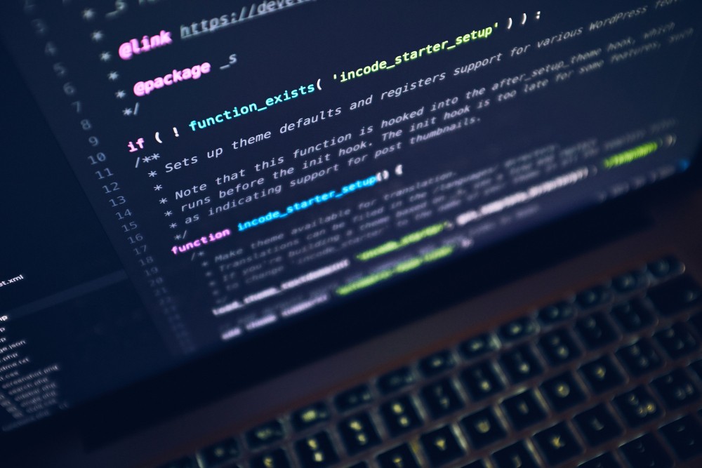 Imagem em close de código-fonte em tela, com trechos como “function_exists” e “decode_startup” destacados em um ambiente de programação, com teclado desfocado ao fundo.